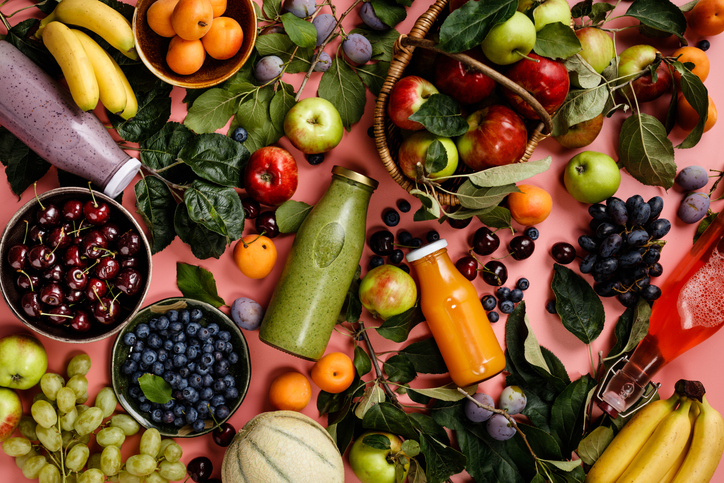 Flat-lay of organic fruits and berries and Freshly blended fruit smoothie on pink background